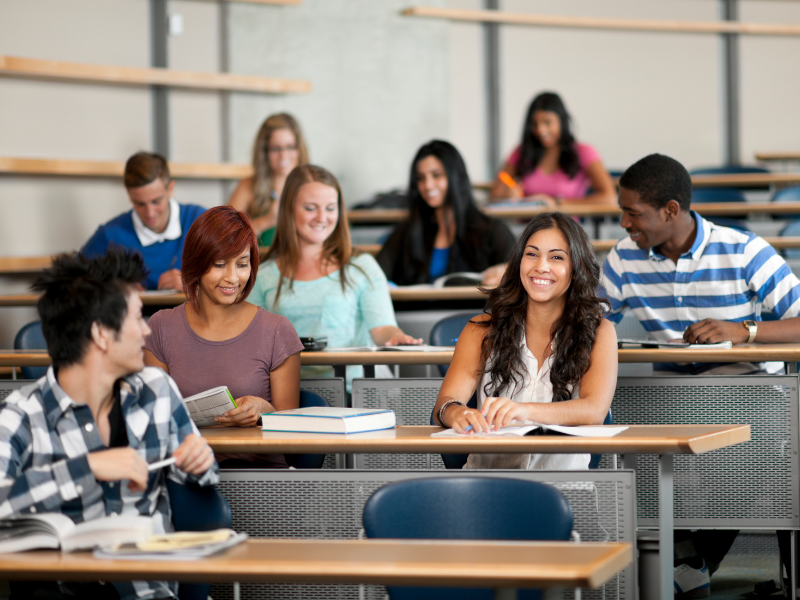 Group of students sitting in a classroom smiling and learning 