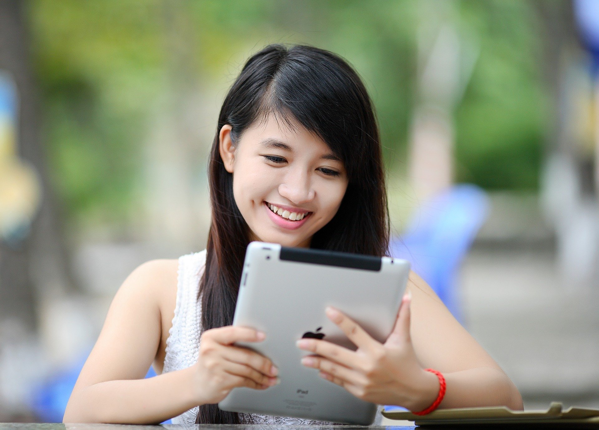 A person using an ipad while smiling outside. 