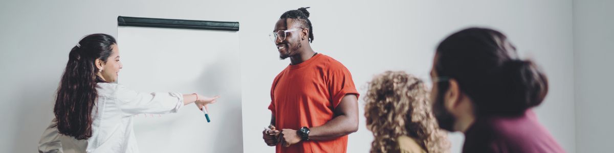 Two people engage in a simulated discussion while two other figures sit watching from a desk.