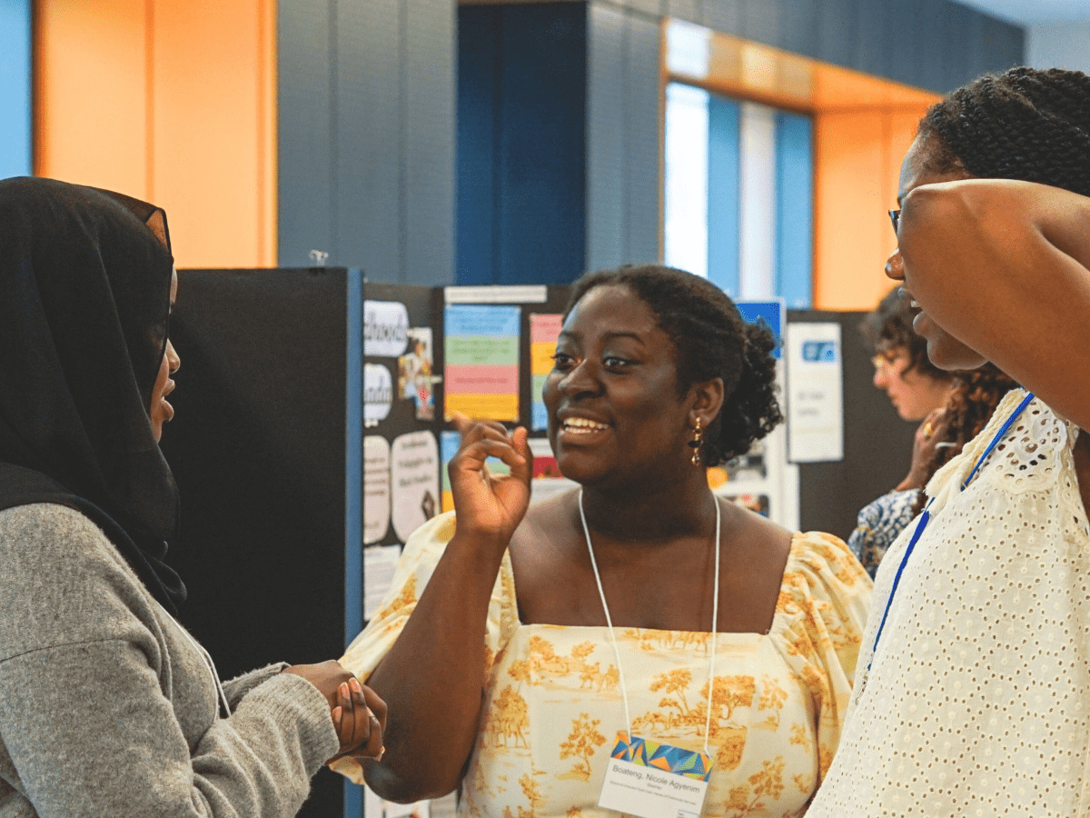 A woman engaged in conversation with two other women at a poster presentation