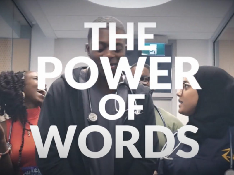 A group of people standing in a classroom. Text reads The Power of Words