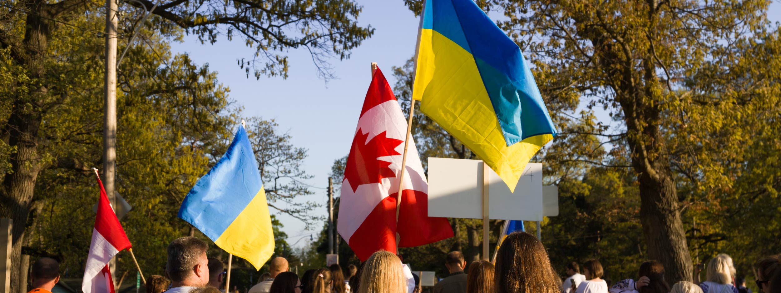 Ukrainian-Canadians marching on a street holding Ukraine and Canada flags