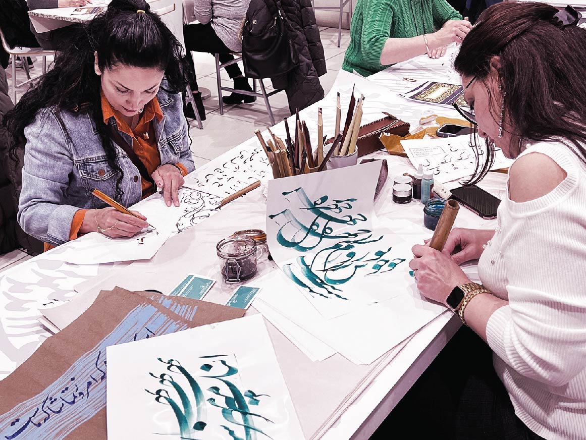 Two women writing in a Farsi calligraphy workshop
