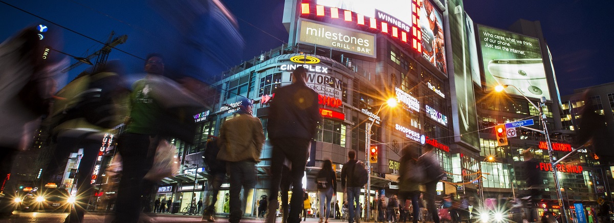Low angle, long exposure photograph of downtown Toronto at night with people walking