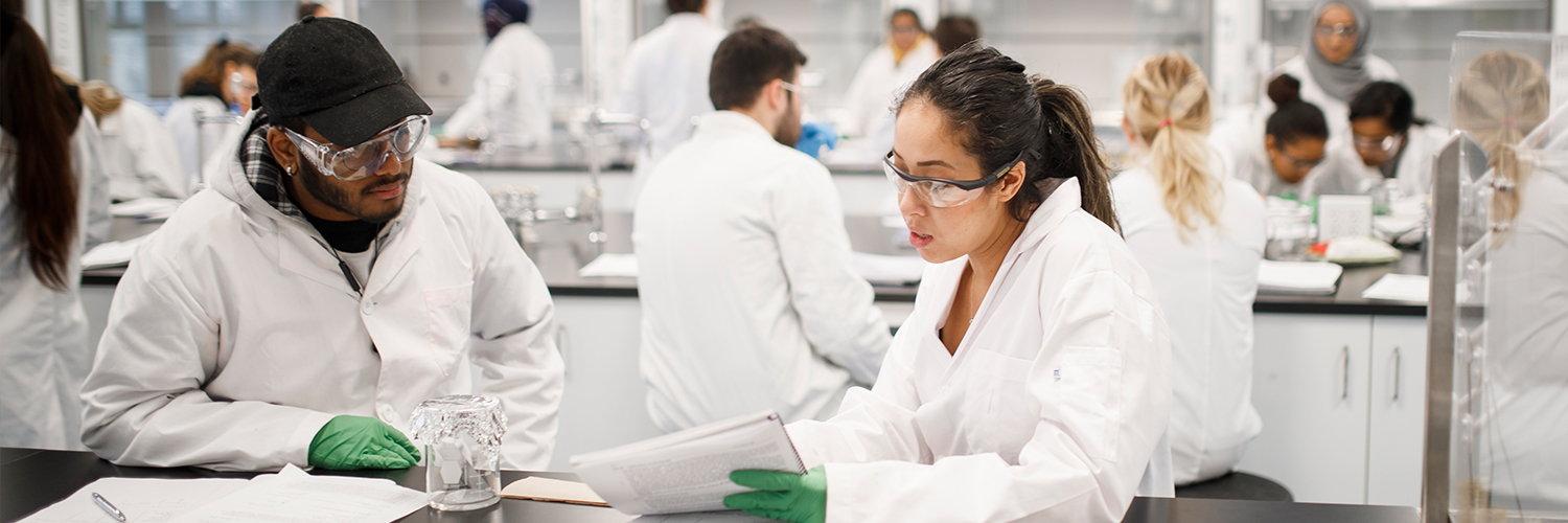 Students in a wet lab looking at notes while conducting an experiment