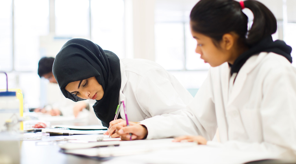 Chemistry and Biology undergraduate students writing notes in lab.