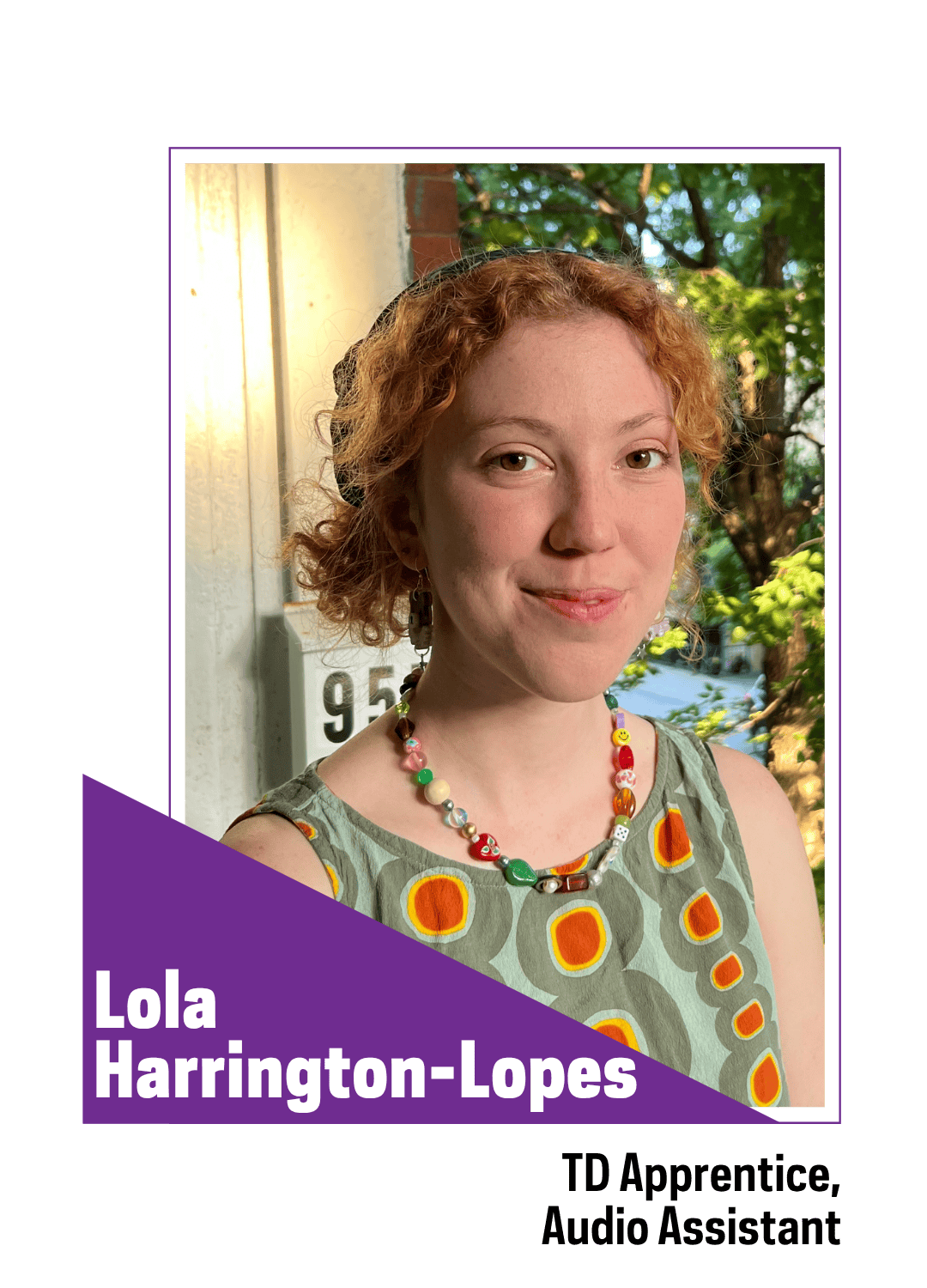 Smiling red haired girl with colorful clothing and jewelry standing outside 