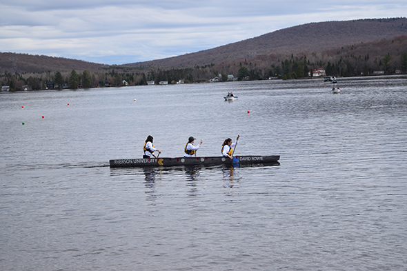 The canadian national concrete canoe team paddling in their canoe on a lake