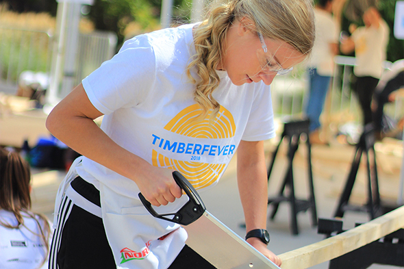 Civil engineering student sawing wood at Timber Fever