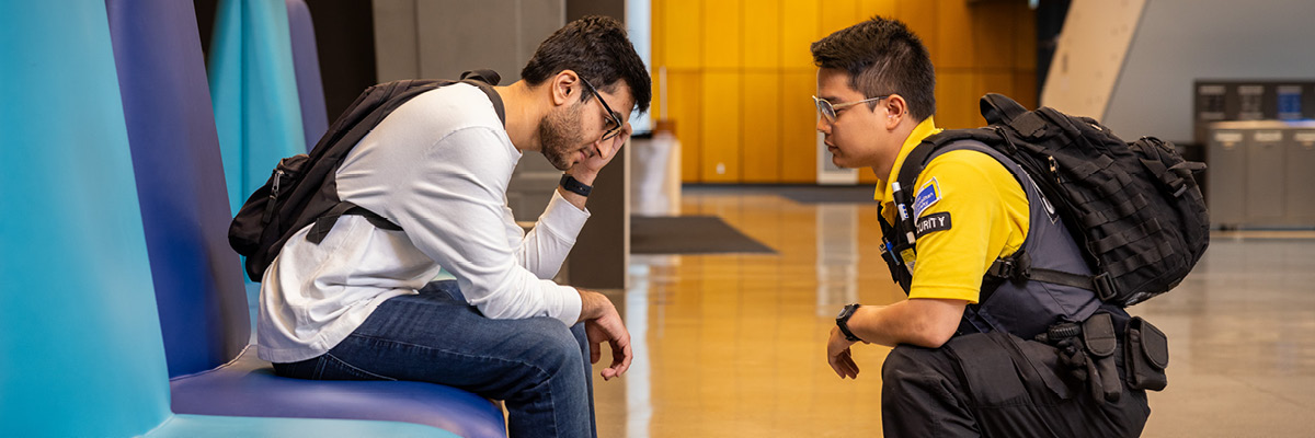 A member of the security team speaking to a person in distress. 