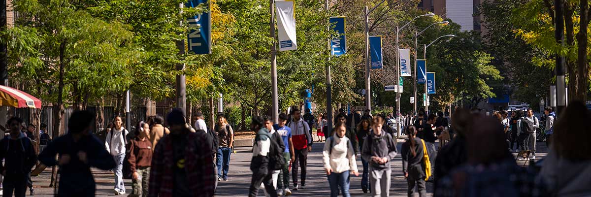 Many people walking along Gould Street with TMU banners on the street poles.