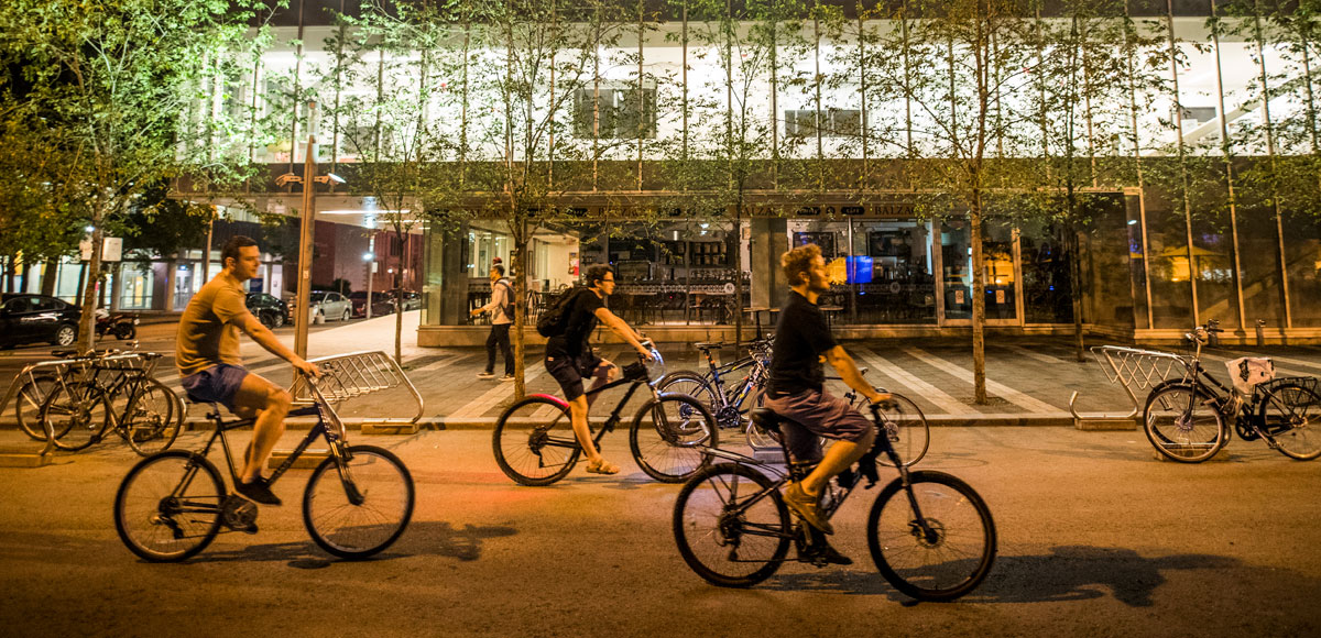 Three people riding their bikes on Gould St in front of the image arts building.