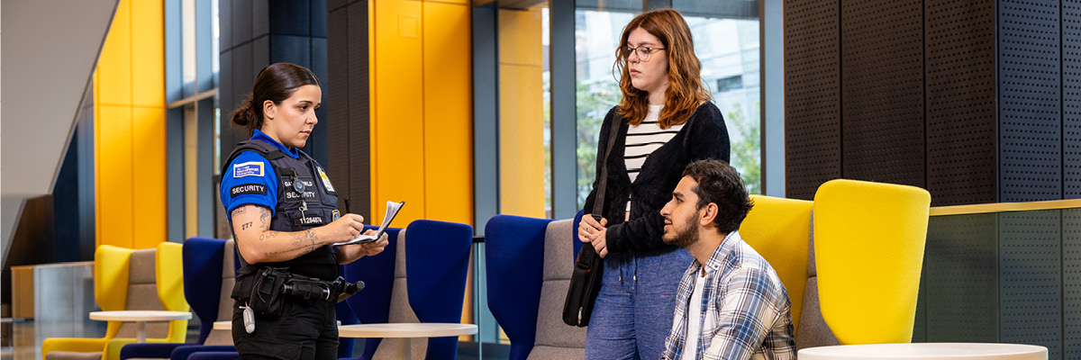 A TMU Security supervisor takes an incident report from two students in the DCC lobby.