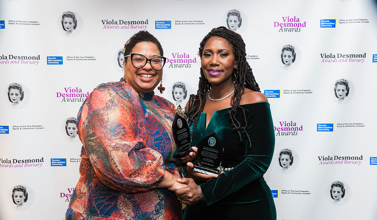 Crystal Mark and Marsha Brown smiling and holding up their awards at the Viola Desmond Awards.