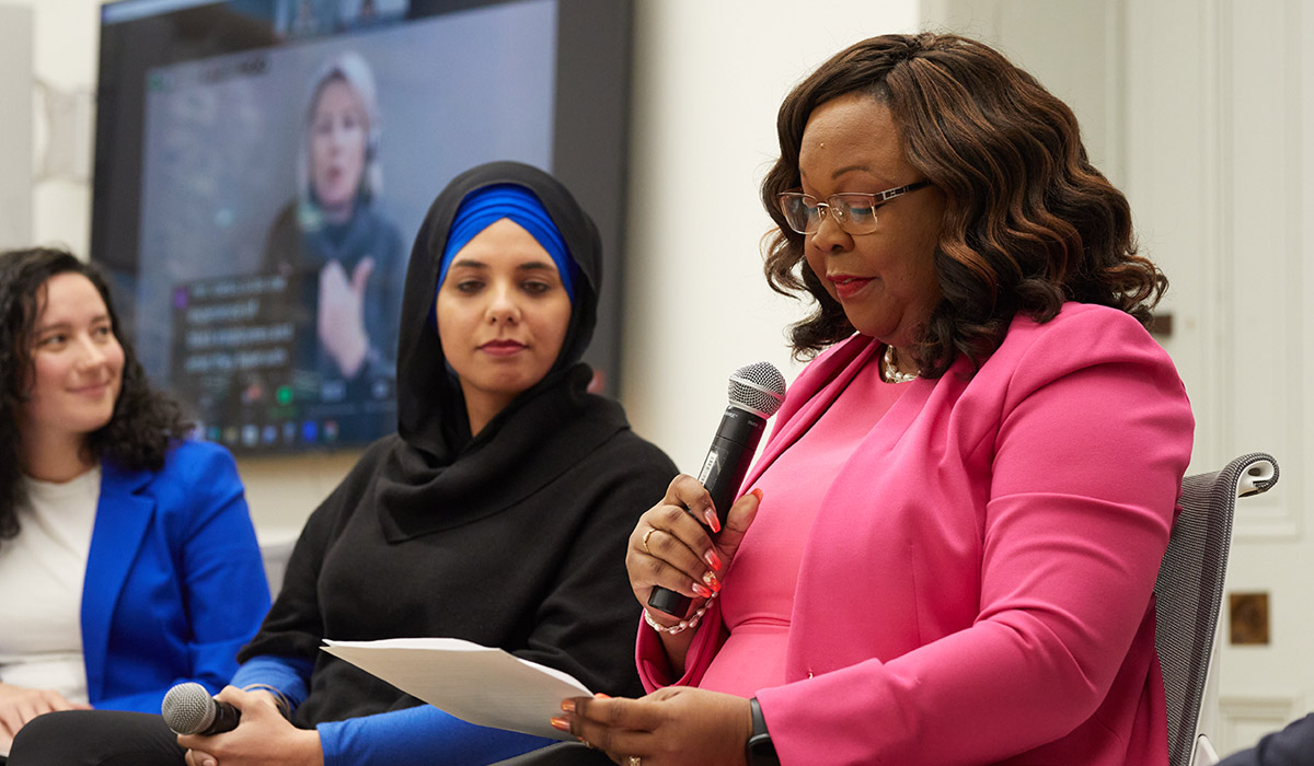 Black staff, Shurla Charles-Forbes, speaking into a microphone at the Innovations in Equity, Diversity and Inclusion Soup and Substance panel. 