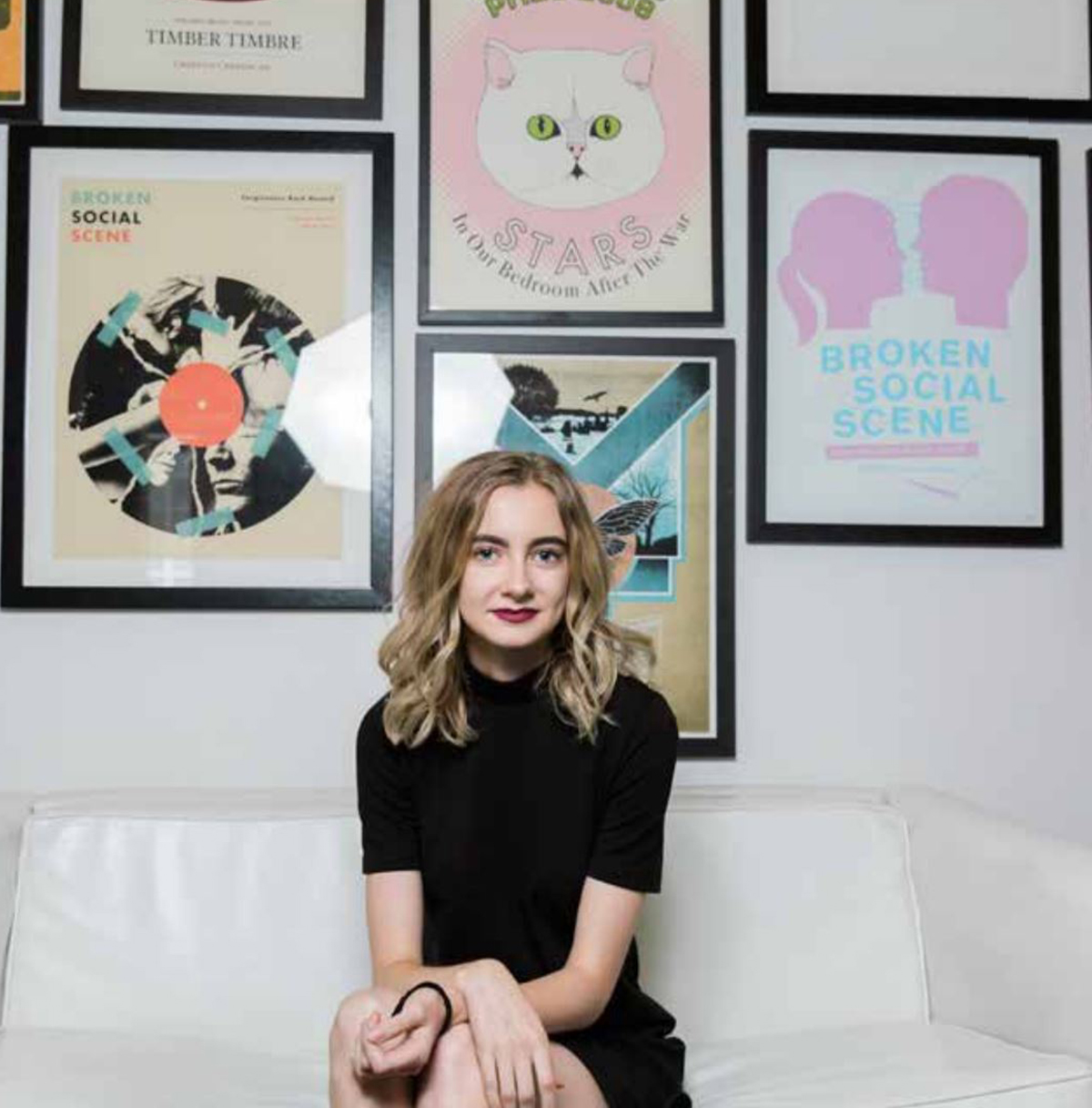 Laura MacMullin sits on a couch surround by photos of album covers at her internship.
