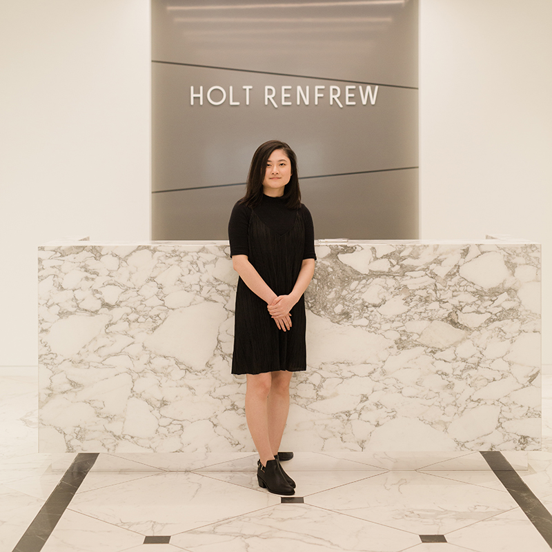 A person standing behind a marble reception desk in a modern corporate lobby.