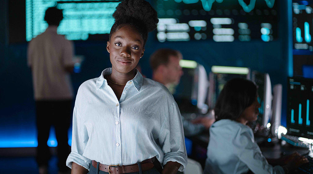 Student smiling while people are working on computers behind her