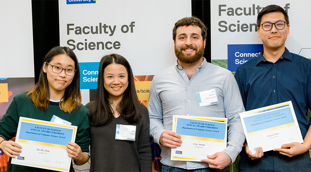 Computer science students posing with awards beside a professor