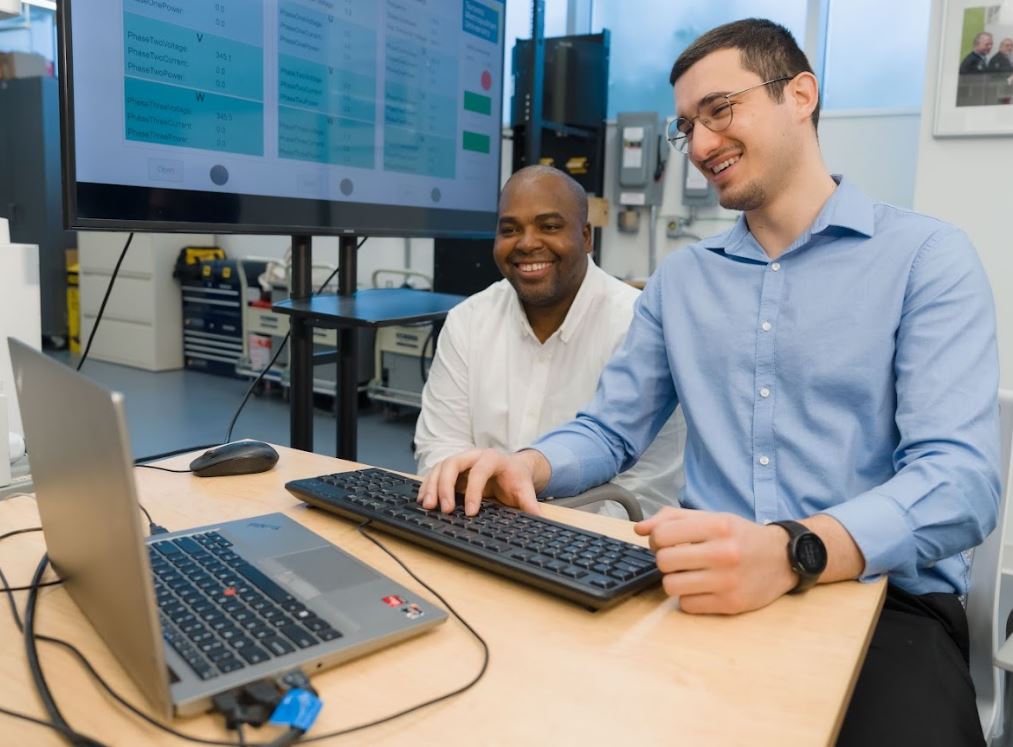 2 researchers looking at laptop together smiling