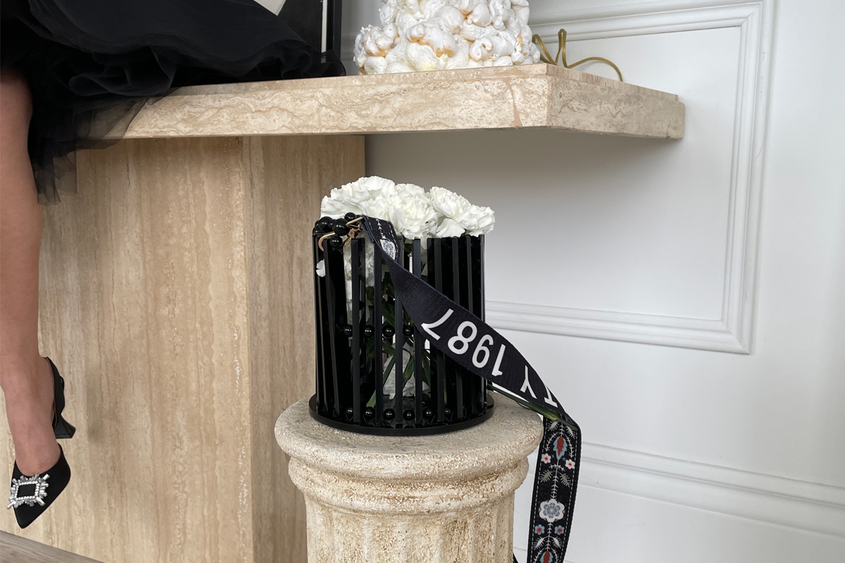 A black cylindrical bag displayed on a stone pedestal. 