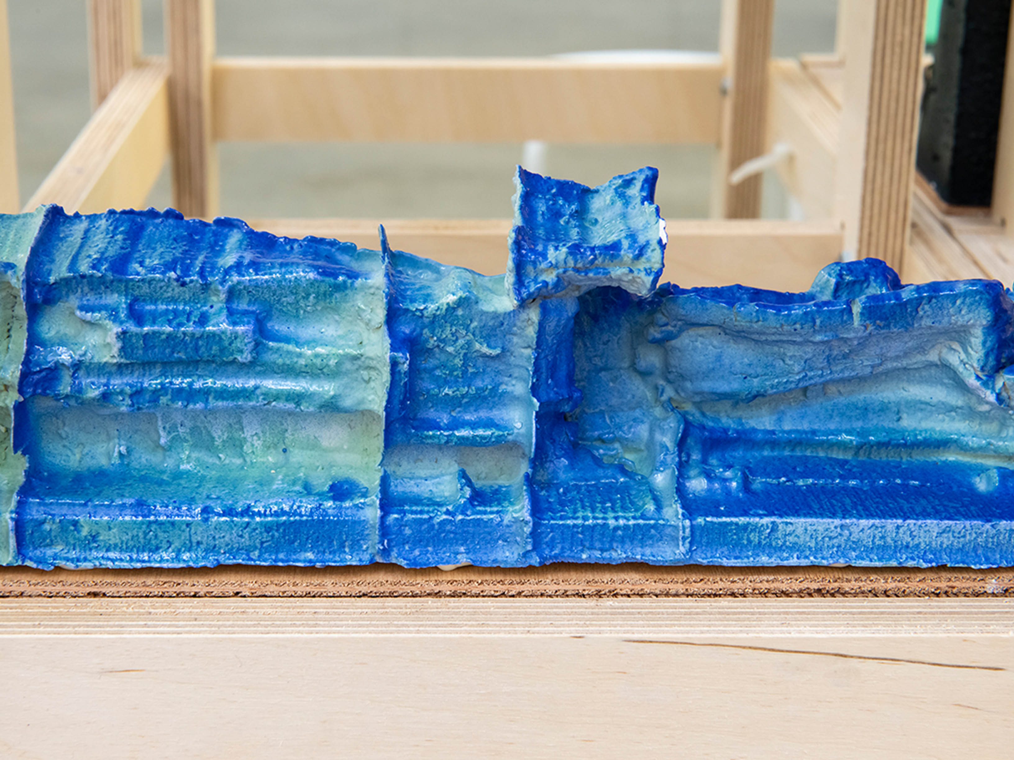 Blocks of blue-glazed ceramic structures resting inside of a wooden frame.