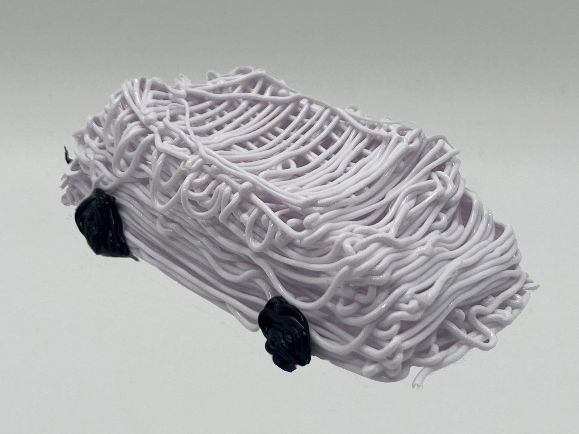 Hand-3D printed white car with black tires. 
