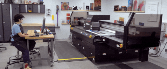 A technician operating a flatbed UV ink printer