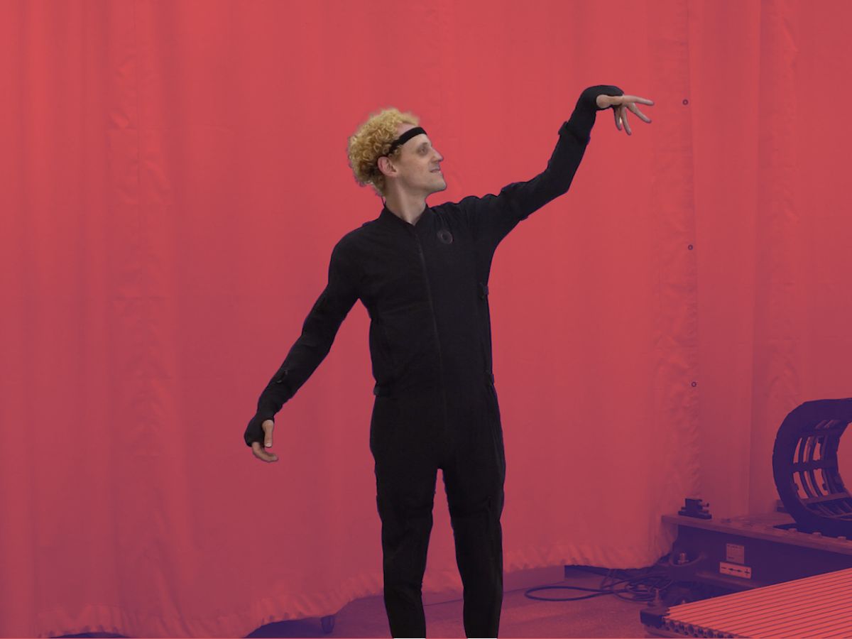 A student in a black motion capture suit raising his arms dramatically. 