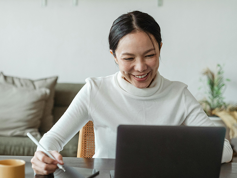 woman smiling while looking at a laptop screen