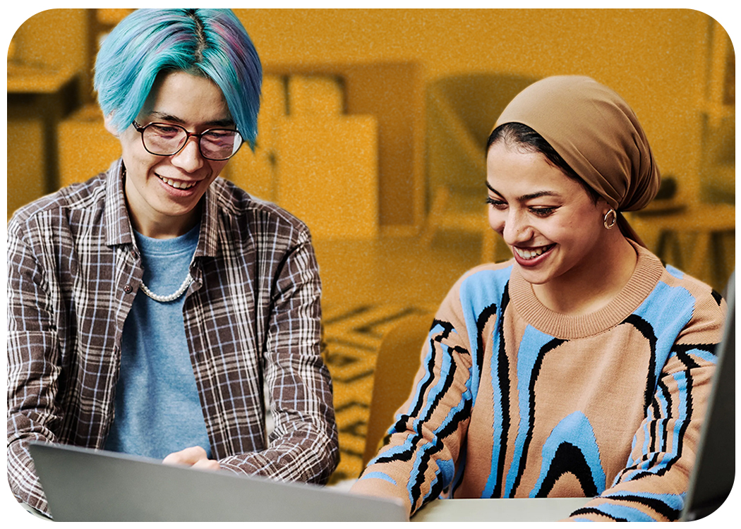 Student and instructor smiling in front of a laptop.