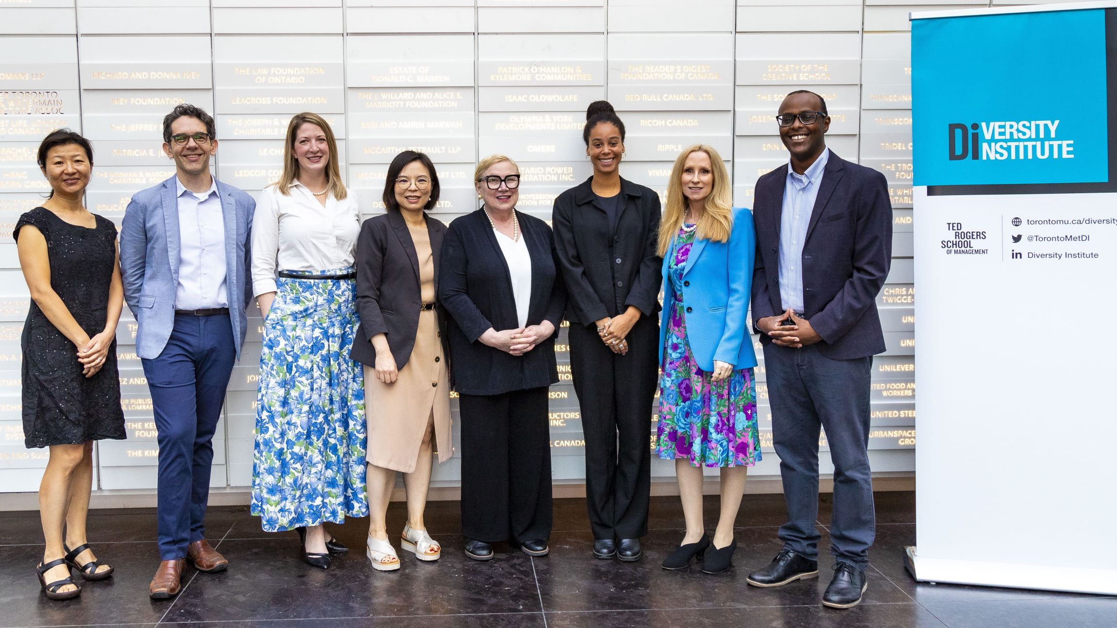 A group of diverse professionals smiling and wearing business attire pose for a photo at a Diversity Institute event.