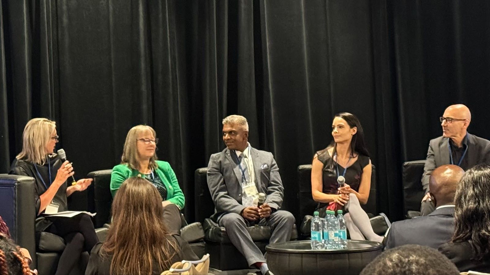 Five people, including two men and three women, are seated on stage as a part of a pannel discussion.