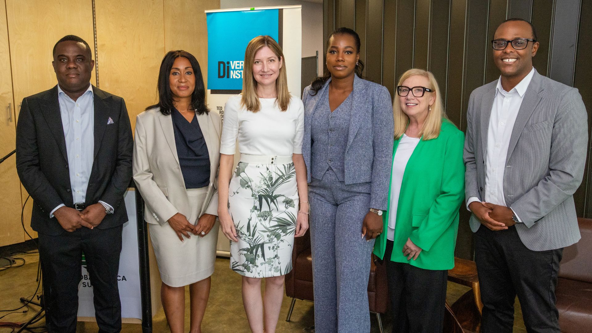 Diverse leaders in professional attire smile for a group image.