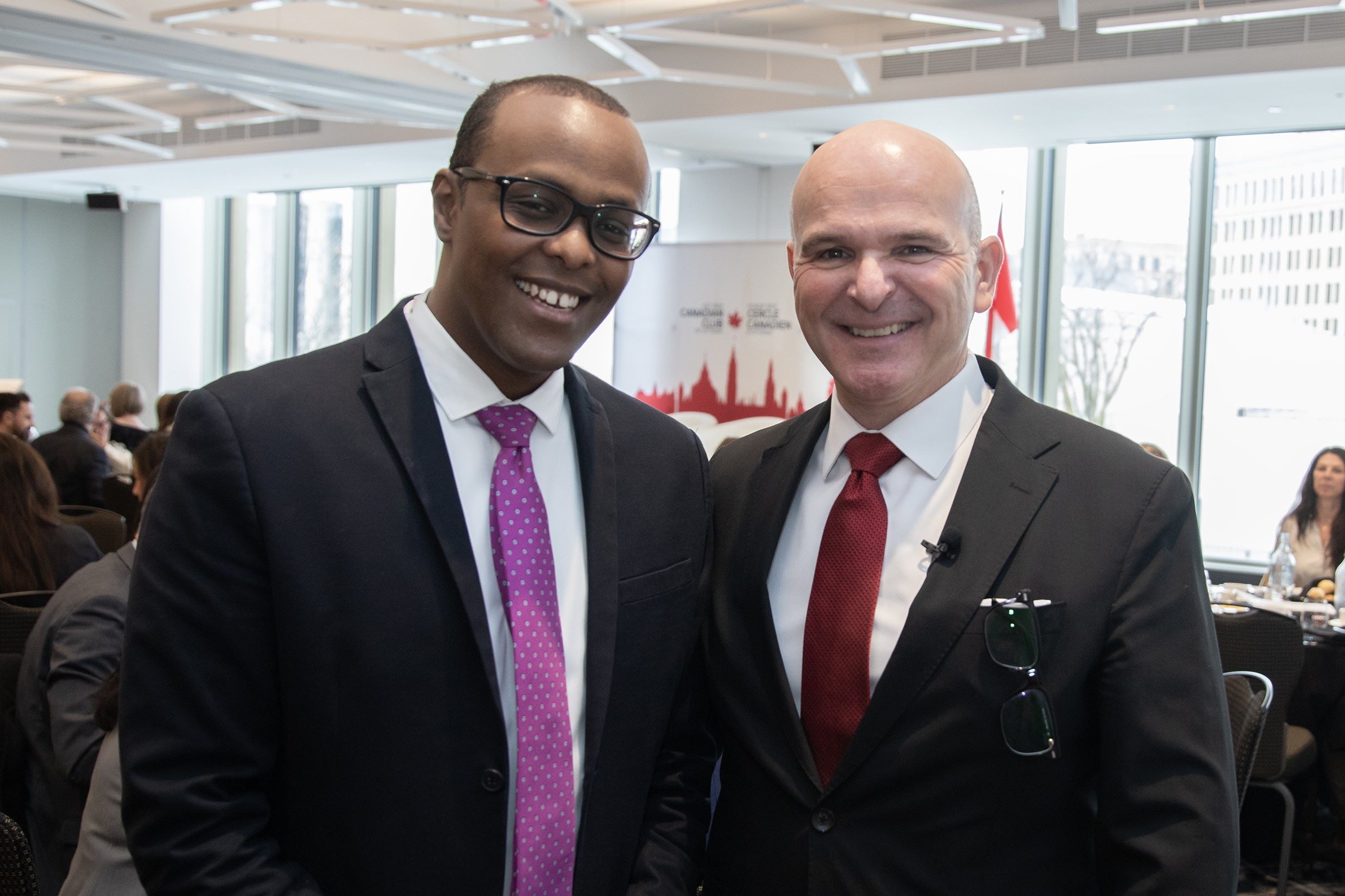 Two men wearing suits smiling at the camera.