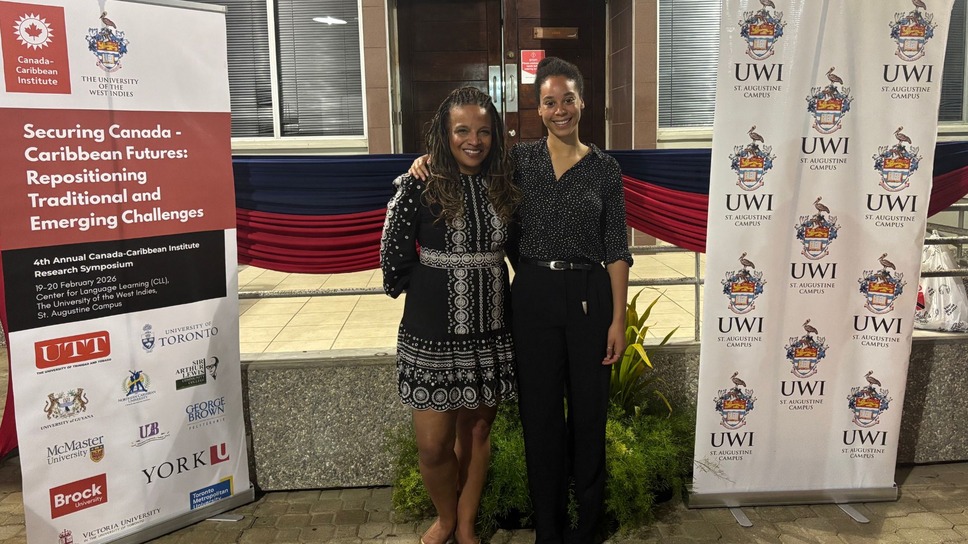 Two women in business casual attire are smiling at a conference. 