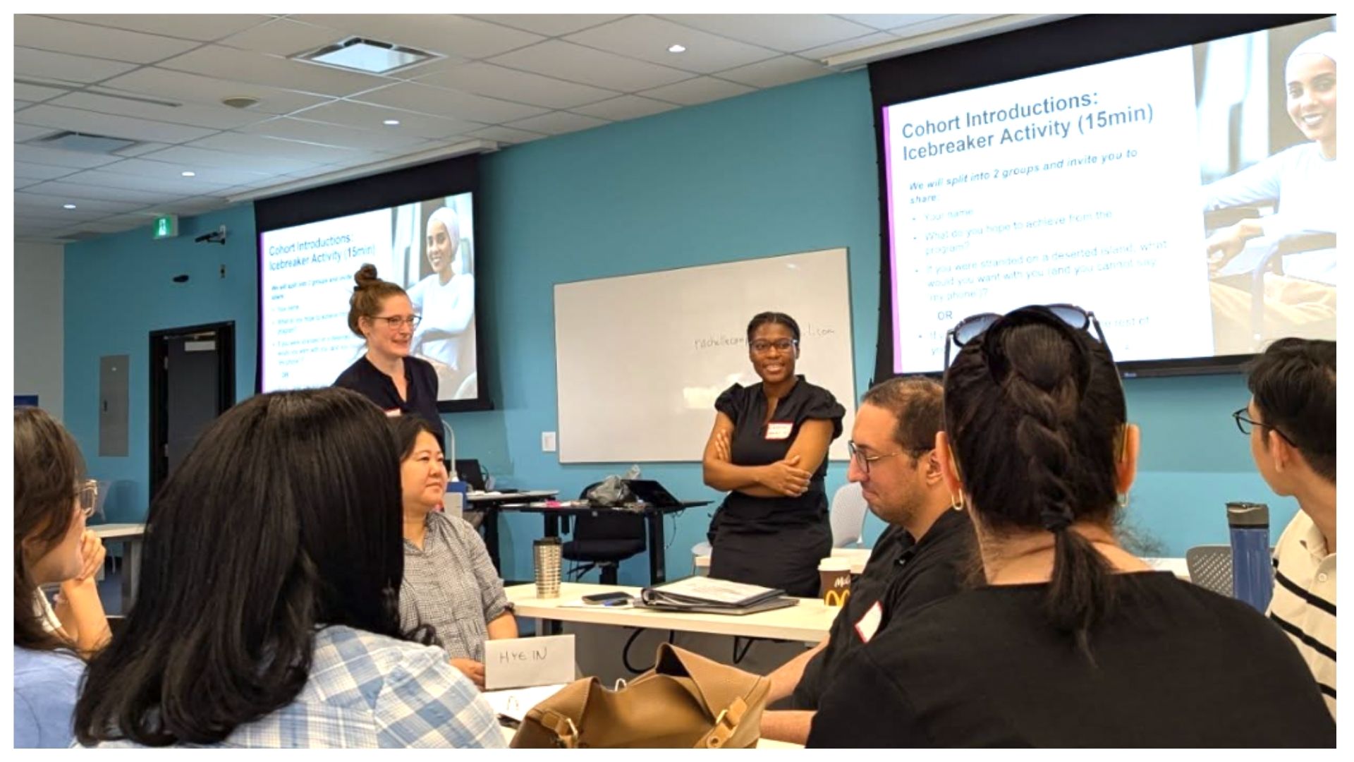 In a classroom, two women lead training for a diverse group of participants.