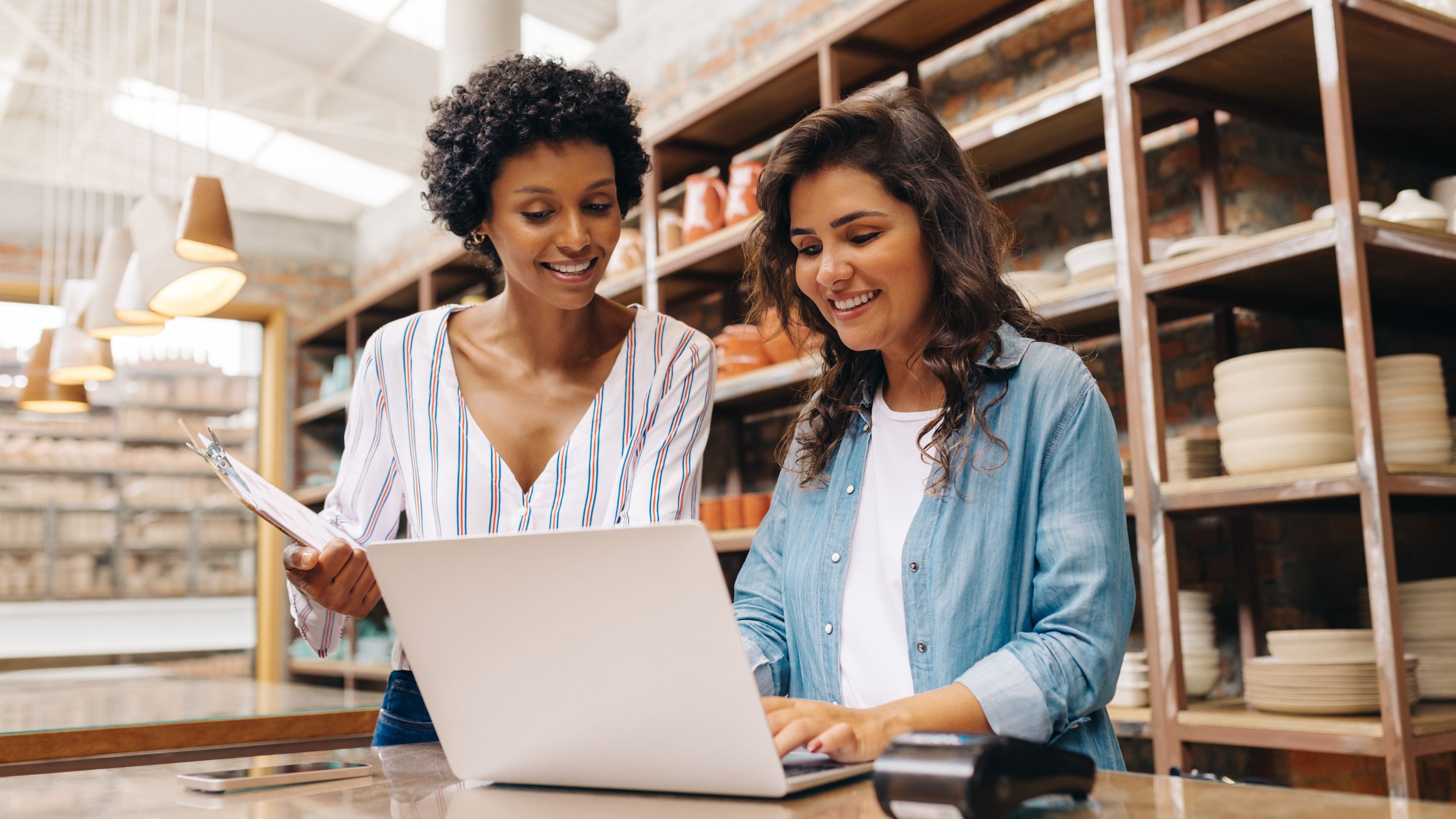 Two women entrepreneurs work over a laptop in a studio.