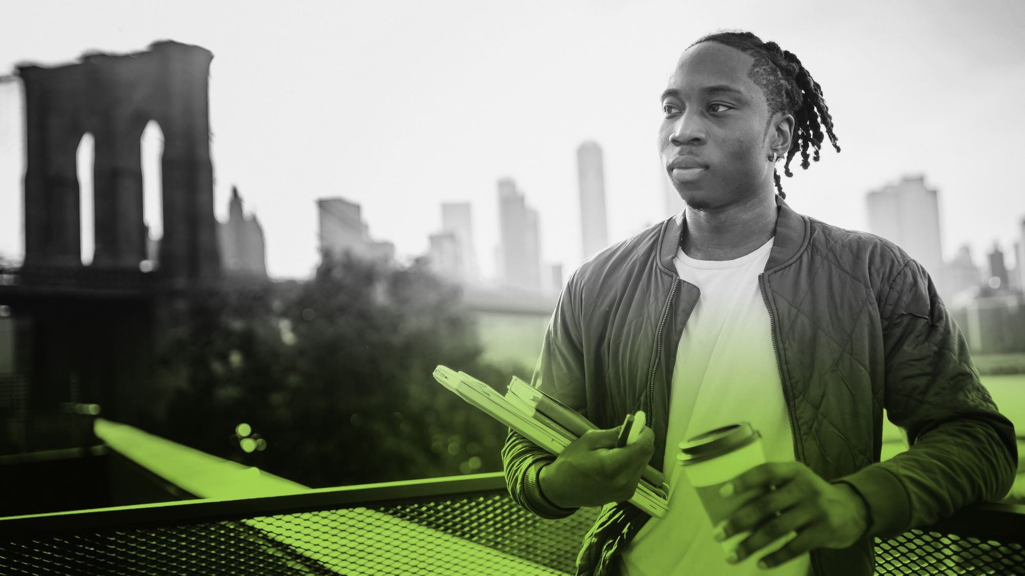 Young man carrying books with a city skyline in the background