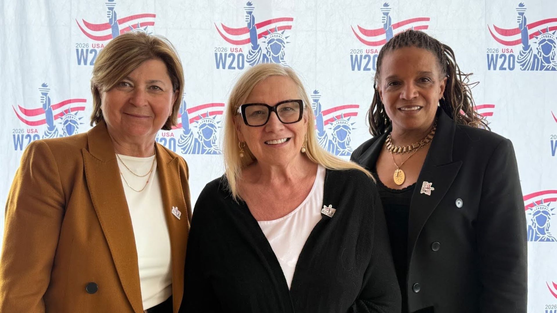 At a Women20 meeting in New York, three diverse business women pose for a photo.