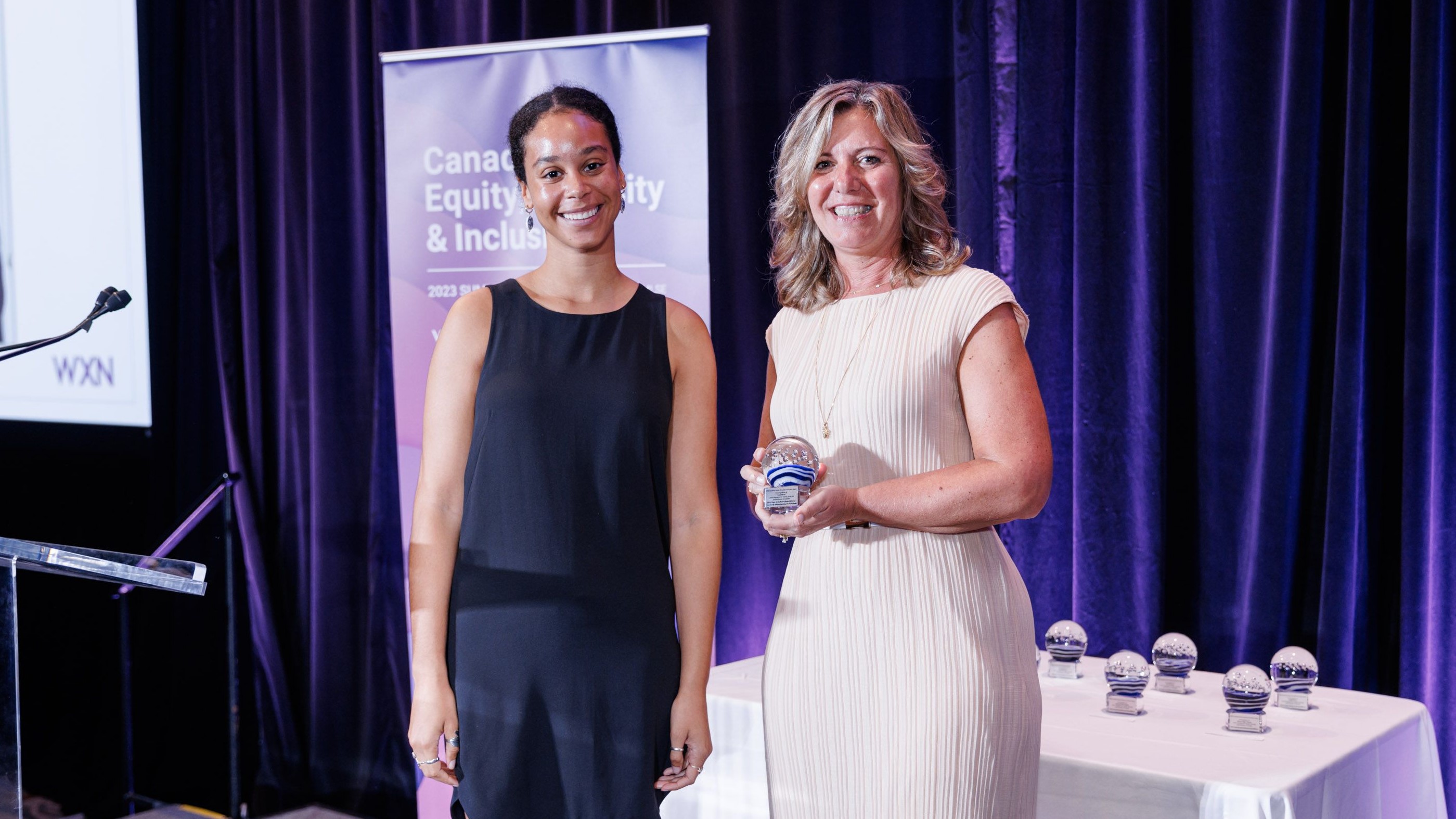 One person gives another an award on stage.