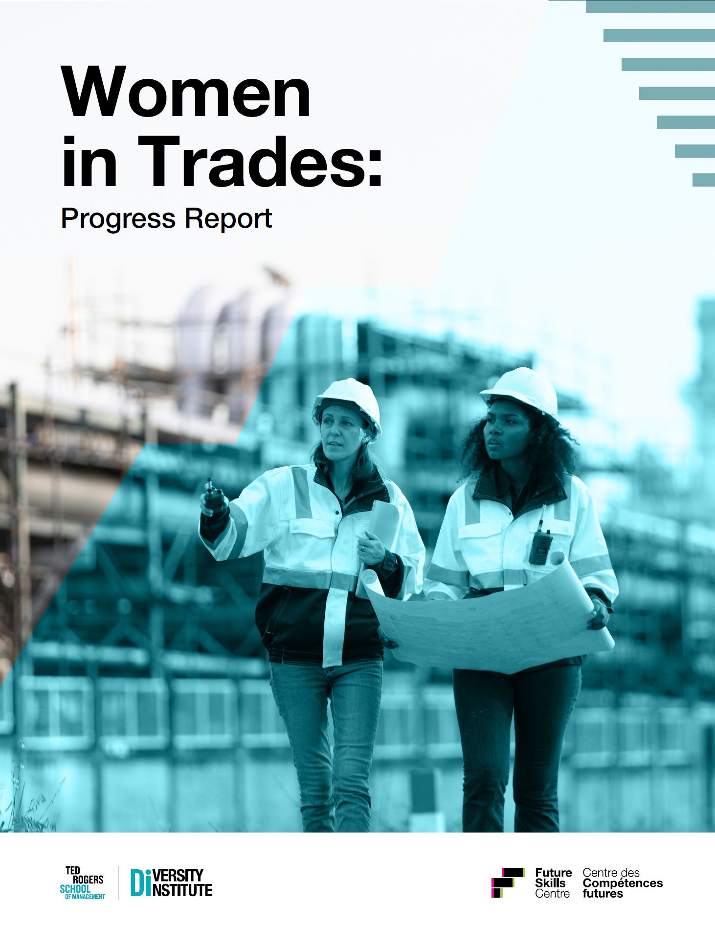 Two women in hard hats walking through a large industrial workplace while discussing blueprints.
