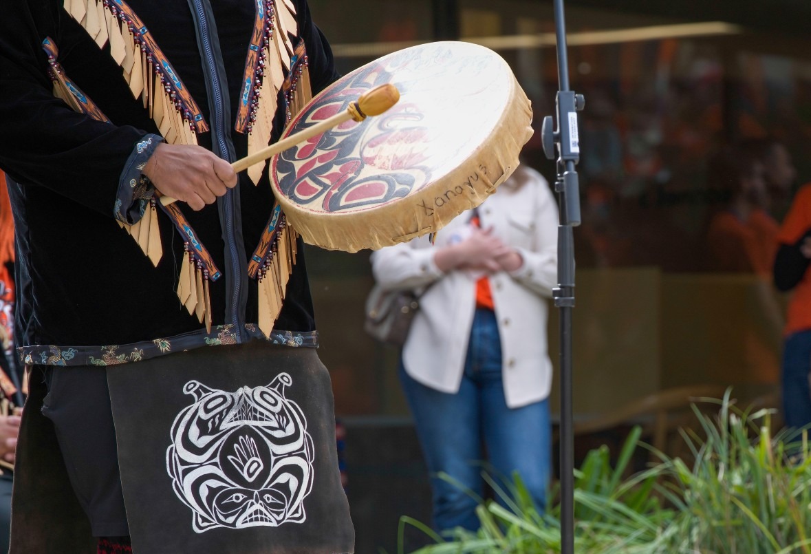 A dancer in regalia from the Squamish Nation in British Columbia, Canada performs with a drum.