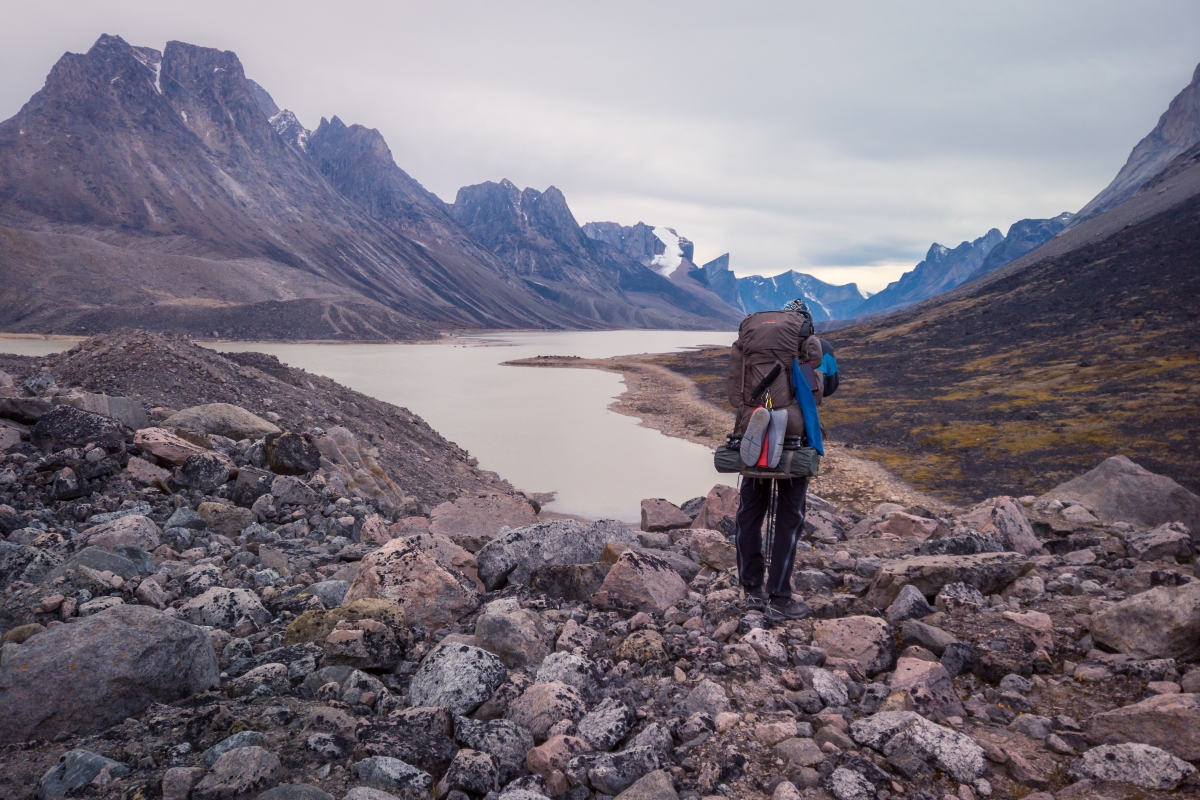 A hiker carefully descends a glacier as he retraces the steps of a rocky mountain