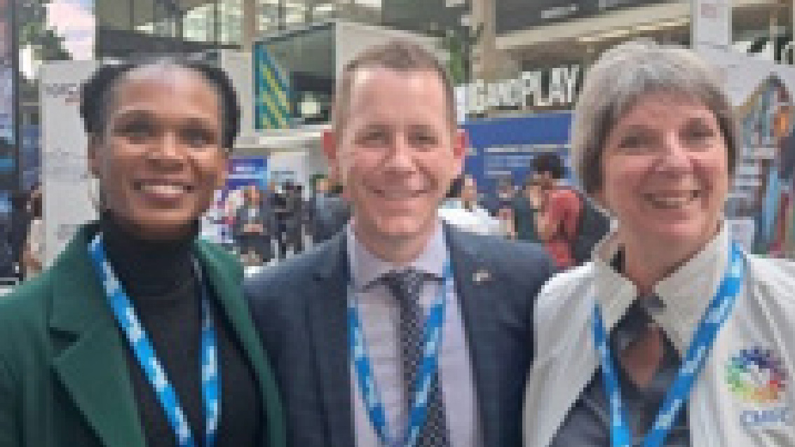 Three women smile and pose for a photo.