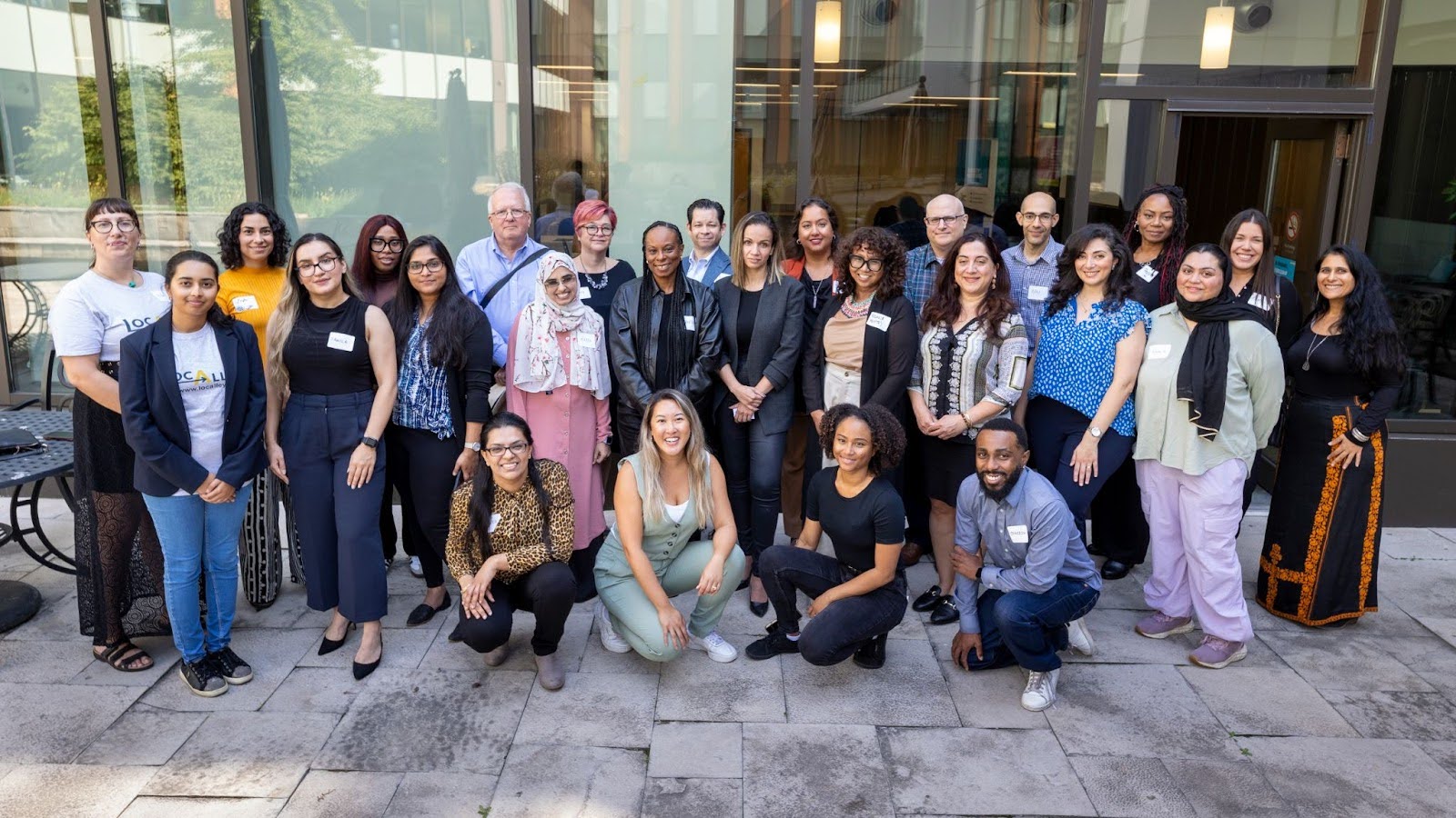 A large group of diverse peoples smile for a group photo.