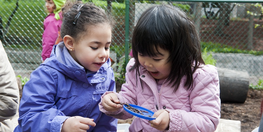Two young girls examine a toy