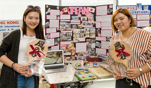 Gina Chang and Eunice Joo are standing near the banner of the Urawa University, Japan