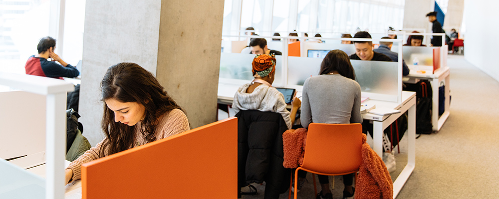 Students study at communal desks in an open work space in the Student Learning Centre building.