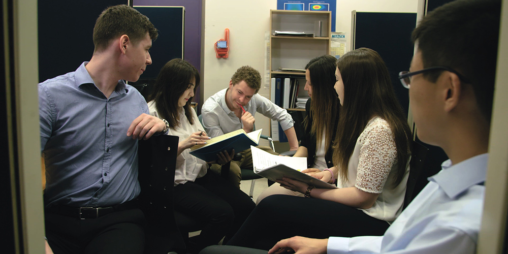 A group of six people, both professors and students, sitting in an office at Toronto Metropolitan University working on a problem